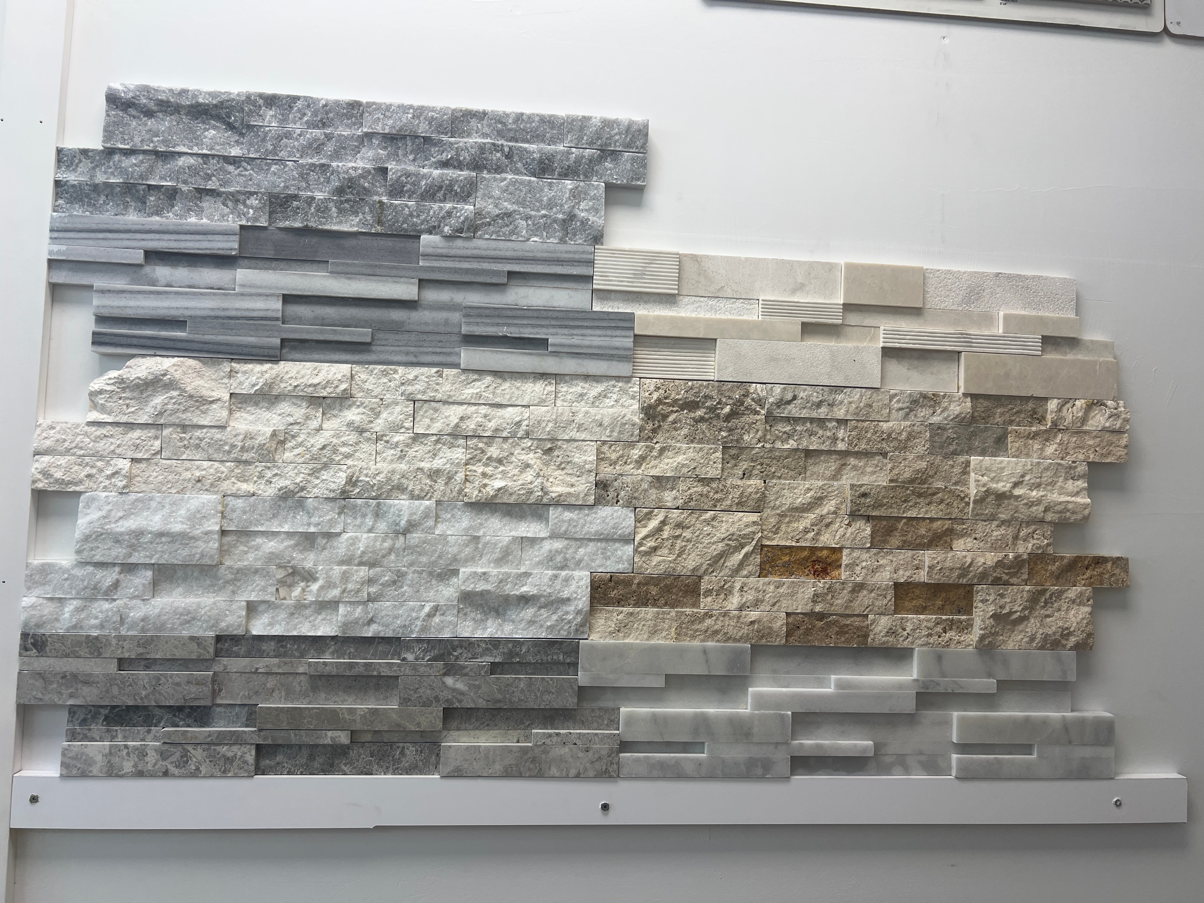 Display de mármol y travertino split-face en gris, blanco y beige dorado con acabados rústicos y pulidos