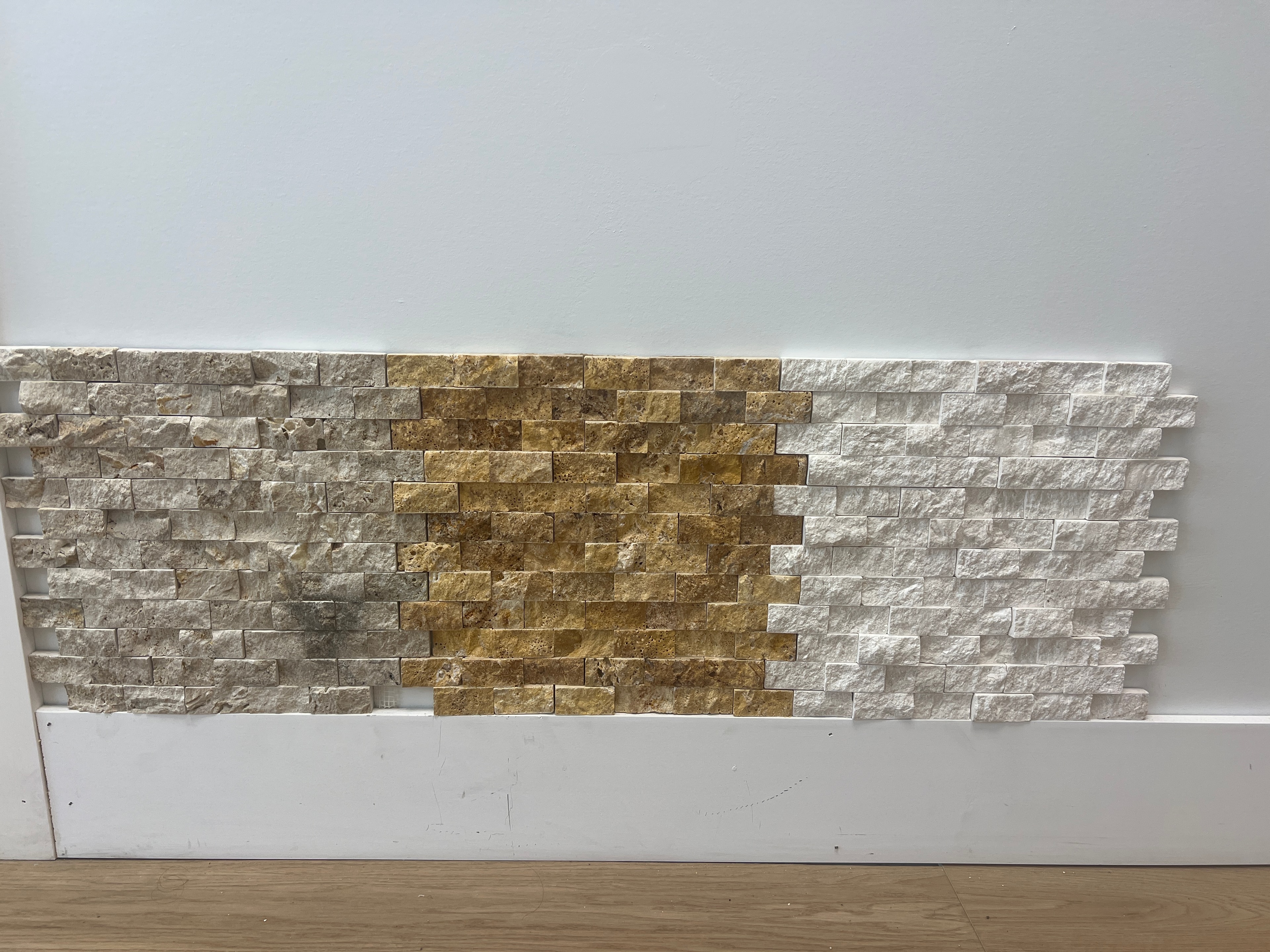 Panel de travertino split-face en tonos beige, dorado y blanco crema — muestra de pared del showroom