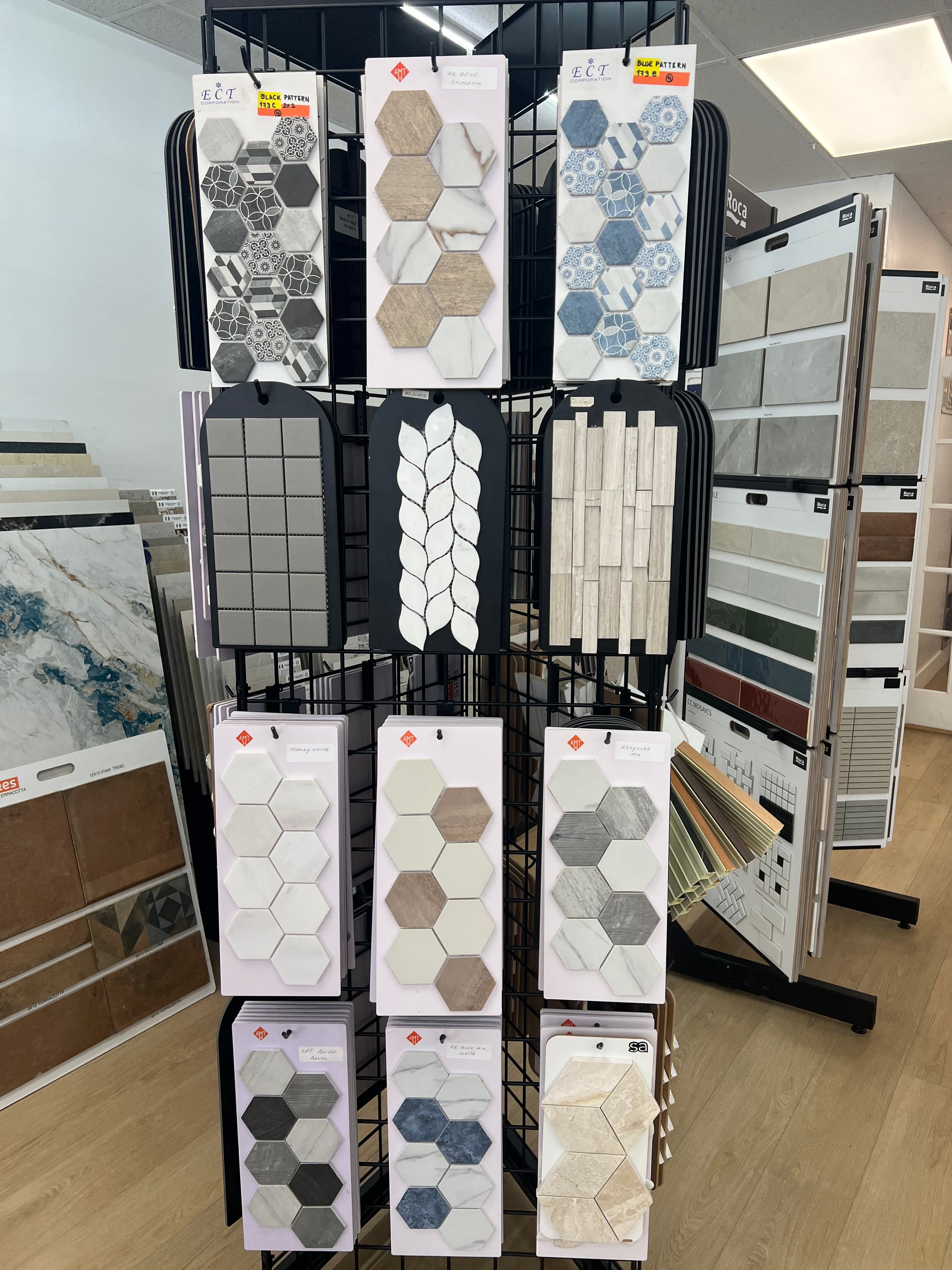 Display de muestras de mosaico hexagonal en tonos azul, gris, beige y blanco con patrones decorativos