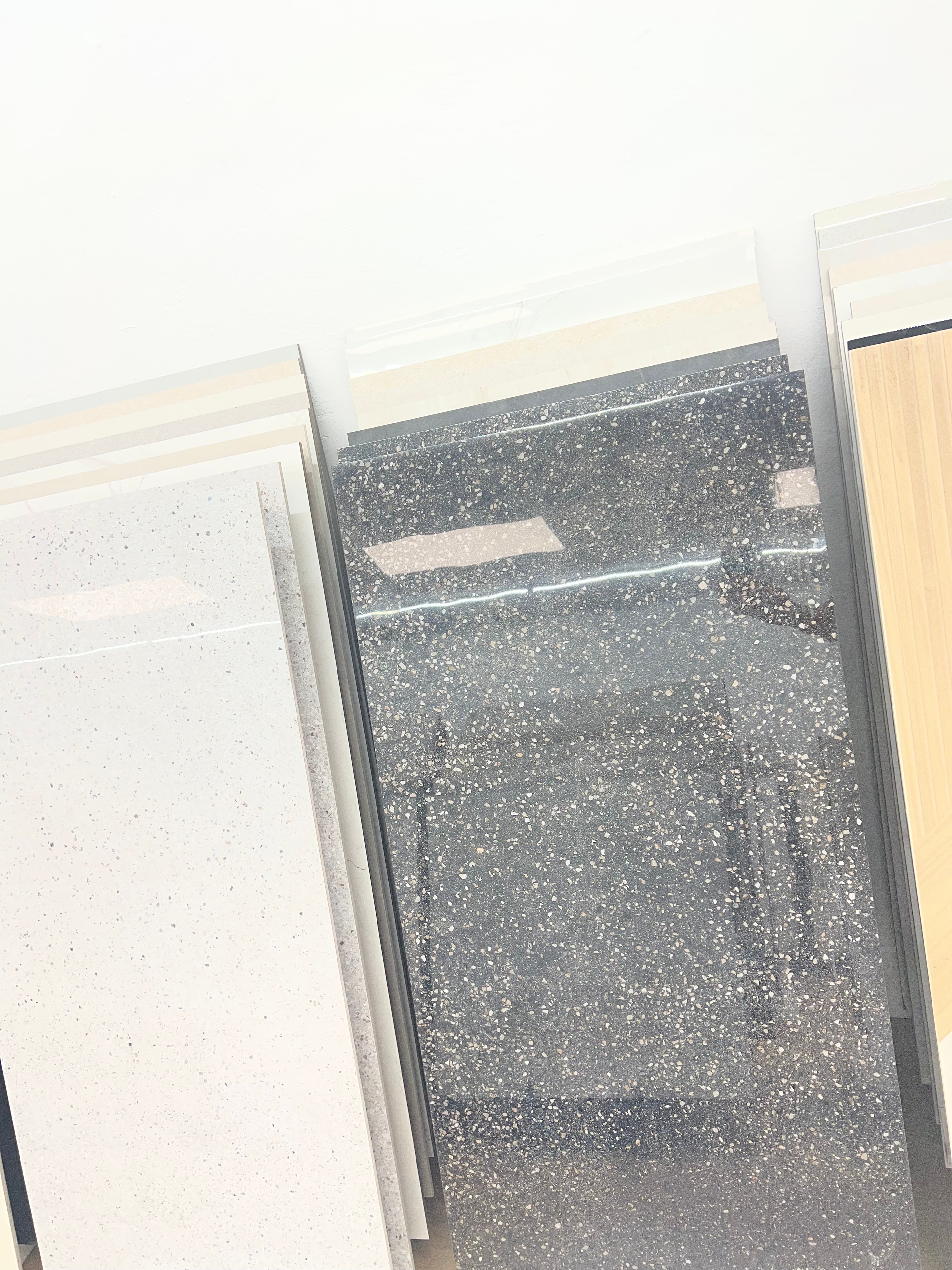 Dark speckled and light neutral porcelain tile samples on showroom display