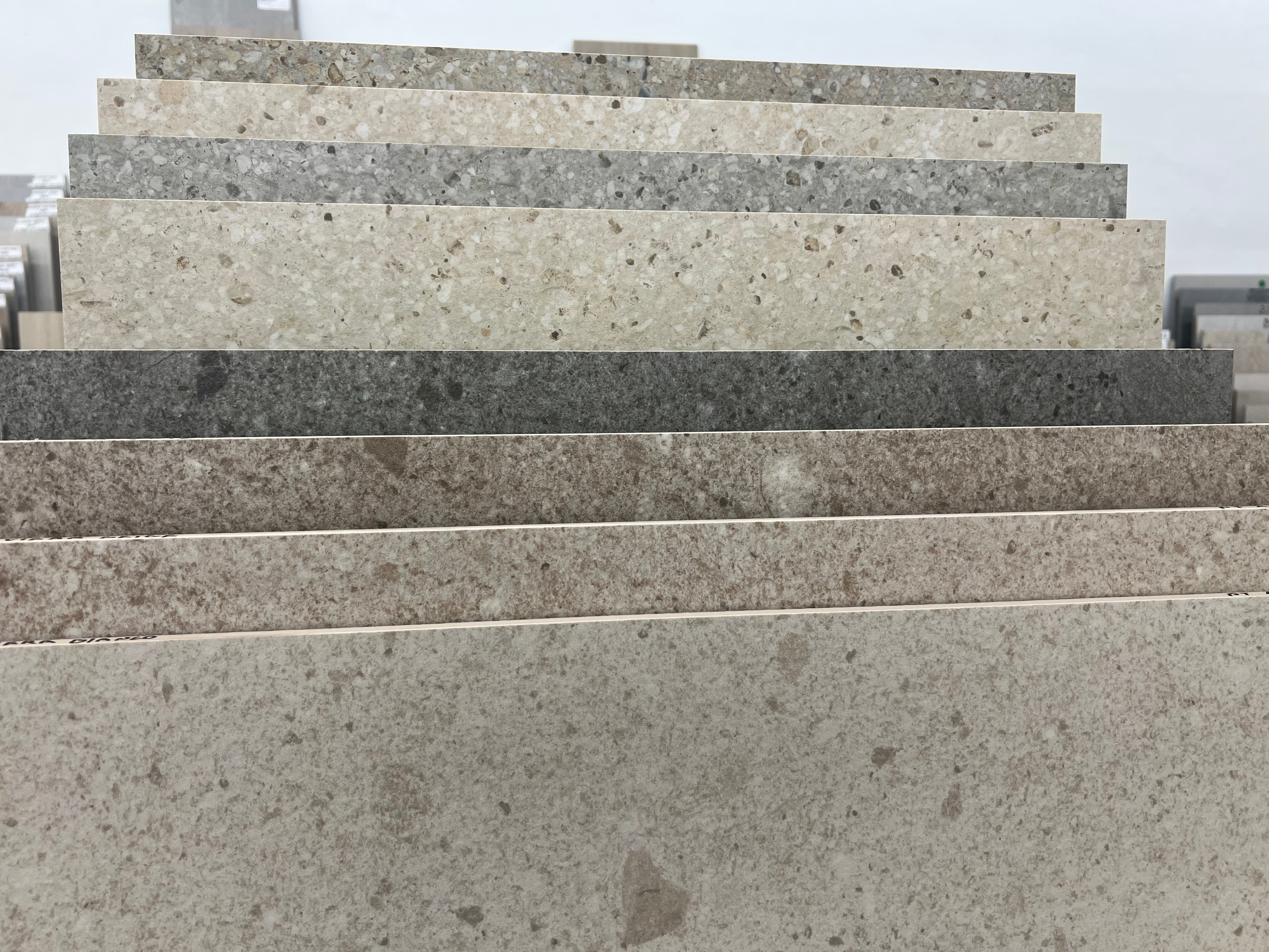 Porcelain tile samples in neutral stone finishes — beige, cream, and gray tones